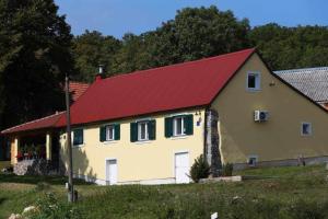 Kuća za odmor Valinčić في Brinje: منزل اصفر كبير بسقف احمر