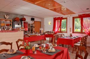 a dining room with red clothed tables and chairs at Logis Hôtel Le Vétiné in Le Valtin