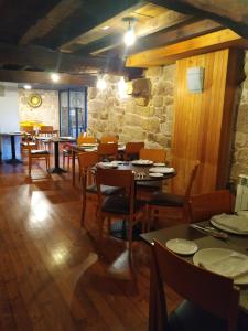 a restaurant with tables and chairs and a stone wall at Pensión rural Pallabarro in Allariz