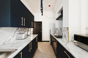 a kitchen with black cabinets and marble counter tops at Captivating 2-Bed Apartment in Liverpool in Liverpool