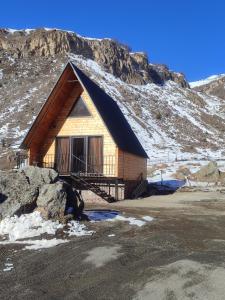 una cabaña de madera con una montaña cubierta de nieve en el fondo en Gold Star en Kazbegi