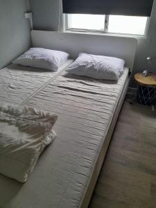 two twin beds in a room with a window at Stacaravan 14 met airco vakantiepark de Tien Heugten Schoonloo Drenthe in Schoonloo