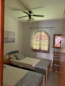una camera con 2 letti e un ventilatore a soffitto di Apartamento Primera Linea de Playa Son Bou ad Alaior