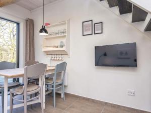 a dining room with a table and a tv on a wall at Holiday home Hovborg XIV in Hovborg