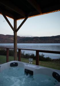 a bath tub with two wine glasses and a view of the water at Shoreland Lodges - Cherry Lodge in Fort Augustus