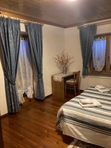 1 dormitorio con cortinas azules, 1 cama y 1 mesa en Monica, en Santo Stefano di Cadore