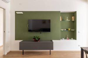 un soggiorno con TV su una parete verde di Valeria Apartment a Bardolino