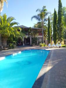 a blue swimming pool in front of a house at Goba Lodge in Gobabis
