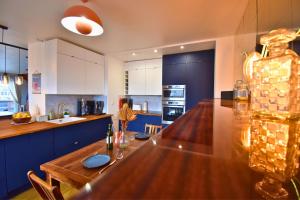 une cuisine avec une table en bois et des armoires bleues dans l'établissement Le Belvédère Parisien, à Aubervilliers