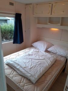 an empty bed in a room with a window at Chalet 426 met airco familiecamping de Tien Heugten Schoonloo Drenthe in Schoonloo