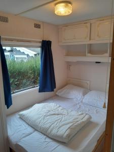 uma cama num pequeno quarto com uma janela em Stacaravan 426 met airco vakantiepark de Tien Heugten Schoonloo Drenthe em Schoonloo