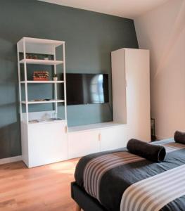 - une chambre avec un lit et une armoire blanche avec une télévision dans l'établissement "Au pied du Beffroi" - Superbe emplacement, à Arras