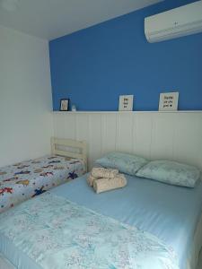 1 dormitorio con 2 camas y pared azul en Studio Morro das Pedras, en Florianópolis