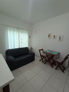 sala de estar con sofá negro y mesa en Studio Morro das Pedras, en Florianópolis