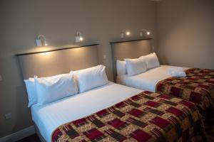 Habitación de hotel con 2 camas con sábanas blancas en Donegal House, en Donegal