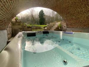 a jacuzzi tub with an arch in a yard at Le Domaine Saint Ange in Friville-Escarbotin