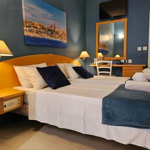 um quarto com uma grande cama branca com paredes azuis em La Playa Hotel em Marsalforn