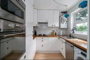 uma cozinha branca com armários brancos e uma janela em 2BD House Canal View and Garden em Londres