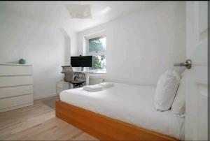 um quarto branco com uma cama e uma janela em 2BD House Canal View and Garden em Londres