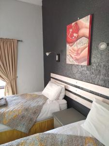 a bedroom with two beds and a painting on the wall at Goba Lodge in Gobabis