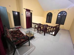 ein Wohnzimmer mit Stühlen, einem Sofa und einem Tisch in der Unterkunft Manasam Homes in Kunnamangalam