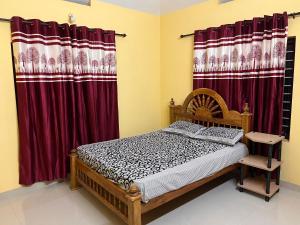 Schlafzimmer mit einem Bett und roten Vorhängen in der Unterkunft Manasam Homes in Kunnamangalam