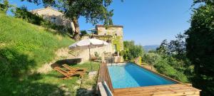 a house with a swimming pool and an umbrella at Borgo Cardaneto in Montone