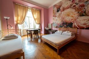 ein Schlafzimmer mit 2 Betten und einem Tisch sowie einem Rosengemälde in der Unterkunft Trzy Kafki Private Rooms in Krakau