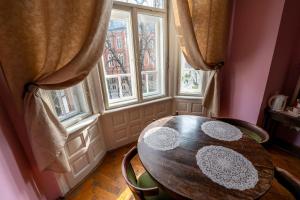 una mesa y sillas en una habitación con ventanas en Trzy Kafki Private Rooms, en Cracovia