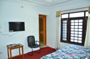 Hotel John's Palace في سريناغار: غرفة نوم بسرير وكرسي ونافذة