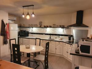 una cocina con armarios blancos y una mesa con sillas. en Maison de campagne, en Amponville