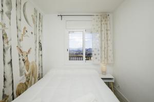Habitación blanca con cama y ventana en Casa con bonitas vistas en Montjuic Girona, en Girona