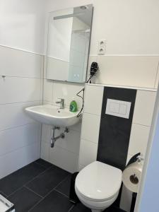 a bathroom with a white toilet and a sink at Hotel Rademacher in Wittmund