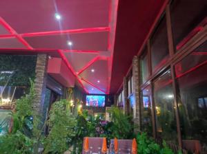 un restaurante con iluminación roja, mesas y plantas en Résidence du goût en Kribi
