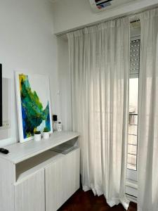 una sala de estar blanca con una ventana con cortinas blancas en Buenos Aires Apartamento ADDA en Buenos Aires
