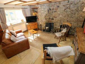 a living room with a couch and a stone wall at 1 Mill Farm Cottages in Narberth