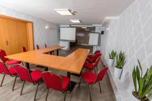 a conference room with a wooden table and red chairs at Hotel Sport in Koszalin