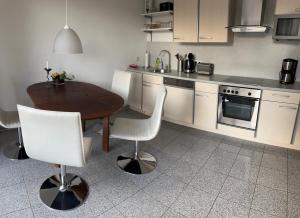 a kitchen with a wooden table and white chairs at Ferienwohnung Am Anger in Naumburg +25 photos