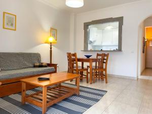 ein Wohnzimmer mit einem Sofa und einem Tisch in der Unterkunft T1 104 - Terraços do Vau in Portimão
