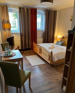 a bedroom with a bed and a desk and a table at Pension Kulturhaus Niederau in Niederau