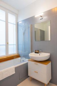 a bathroom with a sink and a tub and a mirror at Appartement Porte de Versailles in Malakoff