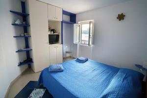カプリにあるLa Casa Dei Merliのベッドルーム(青いベッド1台、窓付)