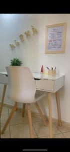 un bureau blanc avec une chaise et quelques lettres sur le mur dans l'établissement Alemà casa vacanze, à Leporano