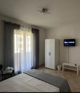 - une chambre avec un lit, une télévision et une armoire dans l'établissement Alemà casa vacanze, à Leporano