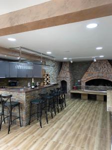 a kitchen with a bar with black chairs and a fireplace at Vikendica za odmor Laktasi in Laktaši