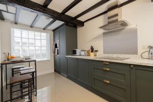 a kitchen with green cabinets and a counter top at The Piano Cottage in a Beautiful Medieval Town in Market Bosworth