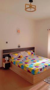 1 dormitorio con 1 cama grande y edredón colorido en Chic minontin, en Cotonou