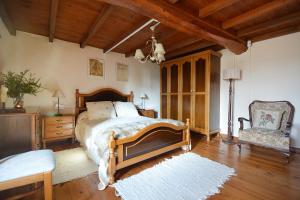 a bedroom with a large bed and a chair at A Casa de Suárez in Negreira