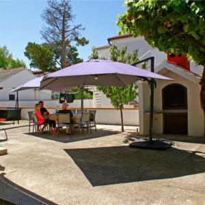 twee mensen zitten aan een tafel onder een paraplu bij Villa Renata in Privlaka