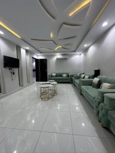 un soggiorno con divani verdi e TV di شاليهات قولدن GOLDEN محايل a Muhayil